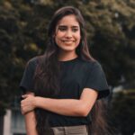 Happy young woman with long hair smiling outdoors in casual attire.